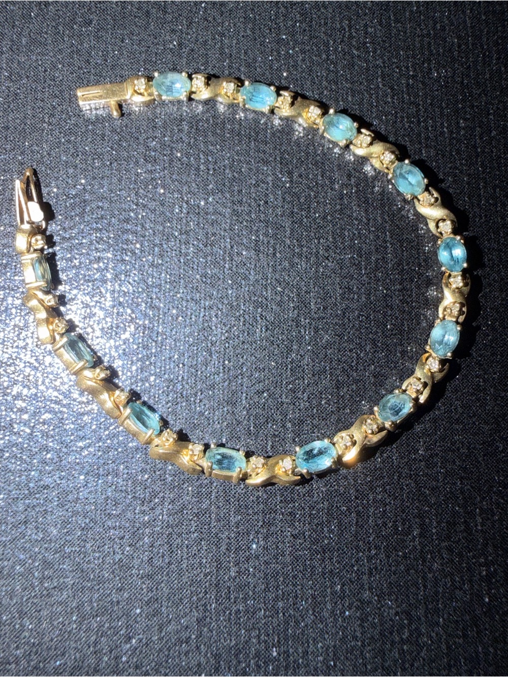 14K Yellow Gold Tennis Bracelet with oval blue topaz stones & diamond accents.